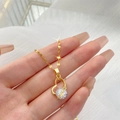 Collier pendentif cœur doré avec grand zircon et gravure LOVE tenu par une main - Cœur avec Lettre