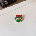 Detail view of a colorful Christmas enamel wreath brooch featuring a cute festive bell design - Flower Garland