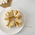 Detailed close-up of champagne gold satin scrunchie displayed on a minimalist white tray - Milk Coffee