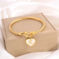 Golden twist bangle featuring a heart pendant with the letter K on a luxury jewelry box - Letter K