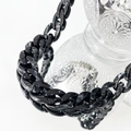 Close-up of black acrylic chunky chain links with glossy finish on a glass bottle - Black Necklace
