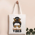 Detail of white canvas tote bag with Halloween pumpkin spice graphics on a wooden hook - PUMPKIN SPICE Vibes Print
