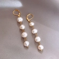 Détail de boucles d'oreilles dorées avec quatre perles baroques sur fond de soie grise - Boucles d'oreilles en perles d'eau douce filetées