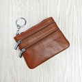 Brown leather coin purse with metal keychain and double zippers on wooden background - Brown