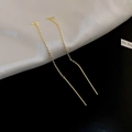 Detailed view of elegant gold long tassel drop earrings on white silk and black background - Chain Threader / Gold