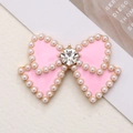 Elegant pink enamel bow charm with pearl border and central crystal on ivory background - Gold Base Pink