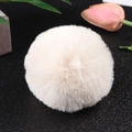 Macro detail of a soft beige faux rabbit fur pom pom with plush texture for accessories - Off White