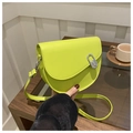 Detail view of neon green saddle bag with silver metal buckle on a wooden table - Green