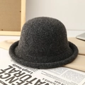 Detail shot of a dark grey knit wool bucket hat with a rolled edge on a stylish newspaper - Graphite Black