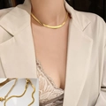 Elegante gouden slangenketting met hartvormige hanger gedragen door model - Gouden Messenketting