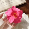 Macro shot of realistic pink hibiscus hair clip on white fabric with natural lighting - Pink