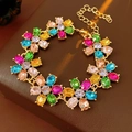 Detail of vintage gold flower bracelet with colorful gemstones on a brown leather background - Bracelet - Multi-colored Flower