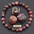 Natural rhodonite beaded bracelet with pink and black patterns on a textured grey background - Rhodonite with Black Lines