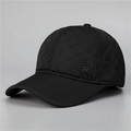 Primer plano del diseño acolchado y logo metálico en gorra térmica de invierno hombre - Ajustable / Negro