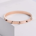 Brazalete punk de oro rosa con tachuelas cónicas en un soporte minimalista - Oro rosa