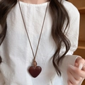 Sautoir rétro avec pendentif coeur en résine marron foncé sur un pull de couleur crème - Style Coeur / Marron