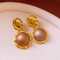 Close-up of vintage gold hammered earrings with brown resin beads on a textured tray - Gold