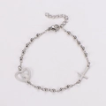 Detailopname van de zilveren kralenarmband met hartvormige hanger en religieus kruis - Staalkleur