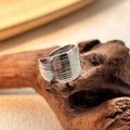 Brede zilveren roestvrijstalen open ring met horizontale geribbelde textuur op hout - Zilver