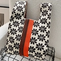 Detail van gebreide draagtas met zwart sneeuwvlokpatroon en oranje-bruine strepen - Zwart & beige 8-bladig bloem