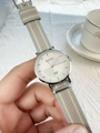 Detail of minimalist quartz watch with tricolor striped canvas strap held in hand - Grey Green Striped