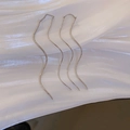Détail de boucles d'oreilles pendantes vagues en argent sur tissu de soie blanc - Argenté