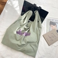 Détail du sac cabas vert clair en tissu gaufré avec lettrage Sora violet et magazine - Vert Gris