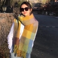 Rainbow plaid plush scarf with fringe tassels worn by a model in soft outdoor lighting - Orange Yellow Blue