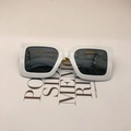 Flat lay of oversized white square sunglasses with dark grey lenses on typographic backdrop - White Frame Gray Lens