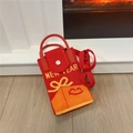 Macro detail of red knitted Christmas mobile bag with New Year text and bow design - New Year Gift Red