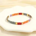 Detail view of multicolored enamel Tila tile stretch bracelet on a white shell tray - BR1670-G/Red Orange Purple Mix