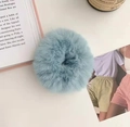 Detail of a fluffy plush scrunchie in light mint green on a white desk with props - Blue