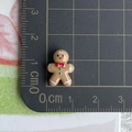 Detailed macro view of 1.5cm gingerbread man resin ornament on a measurement grid mat - 18-Smiling Gingerbread Man