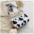 Detailed view of chic cow print underarm bag with zipper closure on a beige blazer - 23*13*7 / Cow Print
