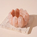 Detail of peach resin cuff bracelet with marble texture on beige stone stand - Pink Marble Resin Bangle
