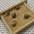 Five brown tiger eye stone oval pendants with metal rings on a bamboo tray background - Picture Jasper