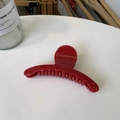 Detail of red glossy hair claw clip with wavy teeth design on a white surface - Red
