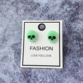 Macro detail of mint green skull stud earrings on a fashion display card - Light Green Skull
