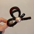 Detalle de la pinza para el cabello trenzada marrón oscuro con una gran perla rosa - Carey (Perla Rosa)