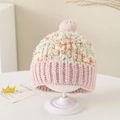 Detail van roze gebreide babymuts met kleurrijke pompon en zachte ribboord - Eén maat / Roze