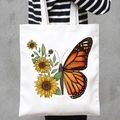 White canvas tote bag featuring butterfly sunflower print worn by a model in stripes - Sunflower Monarch (STD707-U)