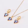 Macro detail of gold necklace and earrings set with iridescent purple heart crystals - Gold