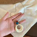 Détail du collier bohème avec anneau crème, perle turquoise et cordon marron à la main - Style 6-Anneau à Perles Blanches