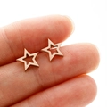 Detailed close-up of mini hollow star earrings in rose gold held to show compact size - Rose Gold