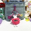 Porte-clés monstre en peluche rose avec lunettes de soleil accroché sur un sac en denim - Rouge pastèque
