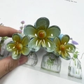 Hair claw clip featuring yellow and green gradient flower design on light blue base - Blue