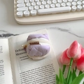 Lavender quilted headphone case for AirPods with pearl zipper charm on marble surface - Light Purple