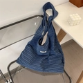 Detailed close-up of blue striped woven tote bag with white label on minimalist chair - Denim Wide Stripe / Blue Stripe