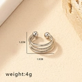 Detail van een zilveren neusring en lipclip zonder piercing op een stenen achtergrond - Drielaagse Kraal Open Oormanchet (BH001-Zilver) / Zilver