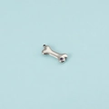 Close-up of silver dog bone pendant with purple zircon inlay on light blue background - Steel February